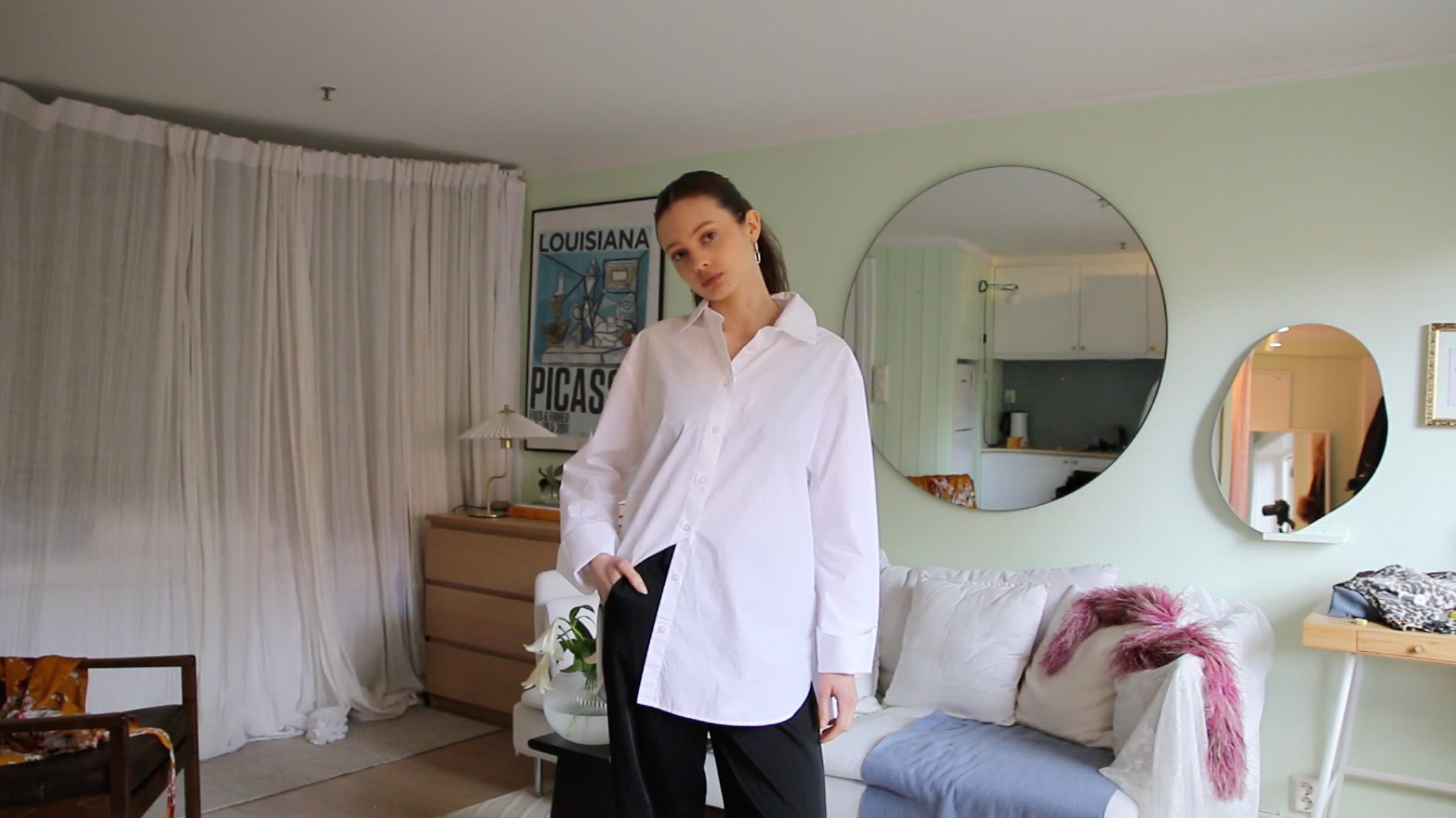 A woman at home in the white shirt she never wears, photographing it as it is.